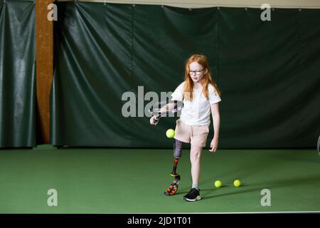 Mädchen mit künstlichem Bein beim Tennisspielen Stockfoto