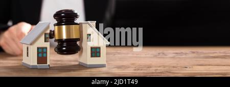 Nahaufnahme eines Richters markante Hammer zwischen Split Haus über Holz- Schreibtisch Stockfoto