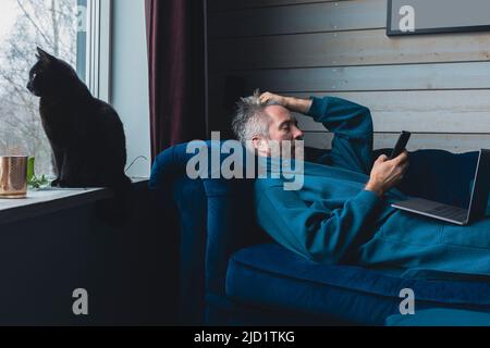 Mann und schwarze Katze entspannen im Wohnzimmer Stockfoto