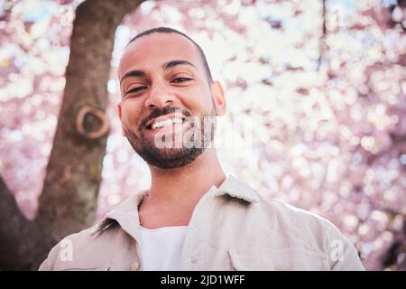 Porträt eines jungen Mannes, der unter der Kirschblüte steht Stockfoto