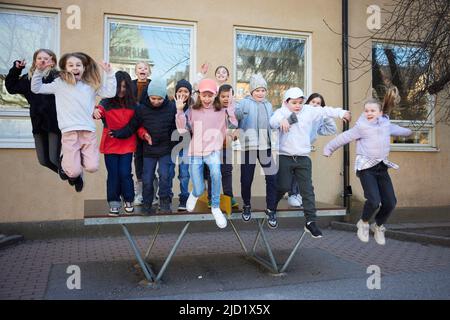 Mädchen und Jungen springen von der Bank Stockfoto