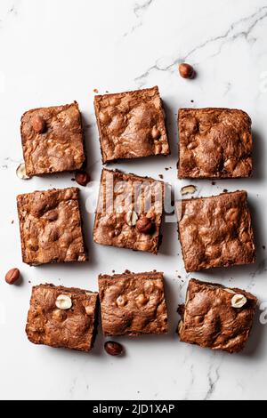 Schokoladen-Brownies mit Haselnüssen auf Marmorboden, flache Lay-Komposition. Draufsicht Stockfoto