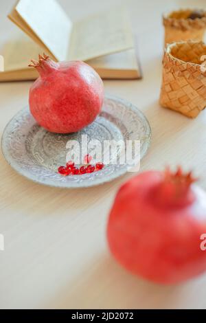 Granatäpfel, Kochbuch, Vitamine auf dem Teller, Tassen auf dem Tisch. Stockfoto
