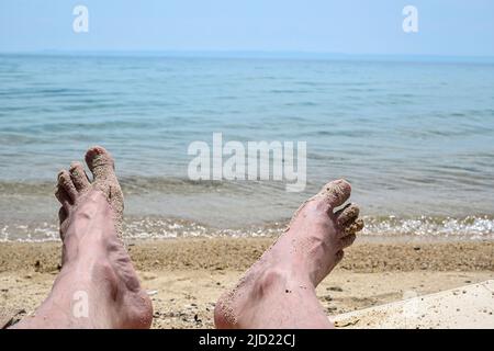 Nahaufnahme der Füße des Menschen, die sich am Meer entspannen Stockfoto