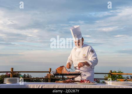 Termoli(CB), Molise Region, Italien: Ein Küchenchef schneidet Schinken von Hand, der als Vorspeise bei einem Hochzeitsempfang serviert wird. Stockfoto