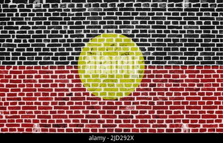 Nahaufnahme einer Backsteinmauer mit der Flagge der australischen Aborigines. Stockfoto