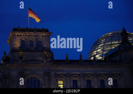 Nachtaufnahme des Reichstags in Berlin. Ein Fenster ist beleuchtet. Eine deutsche Flagge winkt im Wind. Berlin, Deutschland, 1.5.22 Stockfoto
