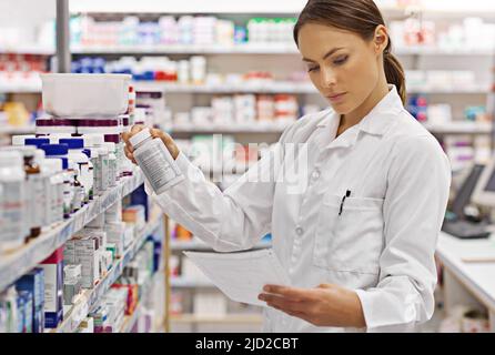 Vorbereitung von Kundenverschreibungen. Aufnahme eines attraktiven jungen Apothekers, der die Bestände in einem Gang überprüft. Stockfoto