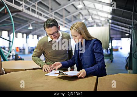 Alles sieht in Ordnung aus. Ausgeschnittene Aufnahme von zwei Mitarbeitern, die ein Lager verwalten. Stockfoto