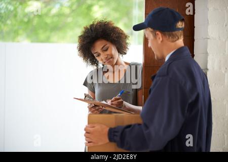 Lieferung direkt an Ihre Tür. Aufnahme eines Kuriers, der eine Lieferung an einen lächelnden Kunden abgibt. Stockfoto
