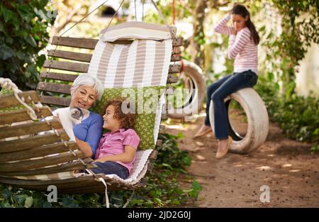 Enkel sind der Trostpreis für das Alwerden. Aufnahme einer Großmutter, die Zeit mit ihren Enkeln im Garten verbringt. Stockfoto