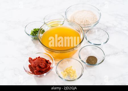 Gemessene Zutaten in Glasschüsseln zur Zubereitung von mexikanischem Reis. Stockfoto