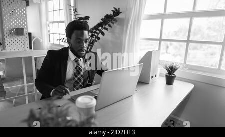 Business African Mann tun Online-Videokonferenz auf Laptop im modernen Büro - Schwarz-Weiß-Schnitt Stockfoto