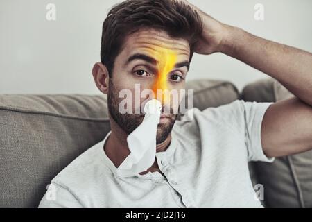 Sieht wieder wie seine Grippesaison aus. Porträt eines unglücklichen jungen Mannes, der aufgrund von Nasennebenproblemen ein Gewebe in der Nase trägt. Stockfoto