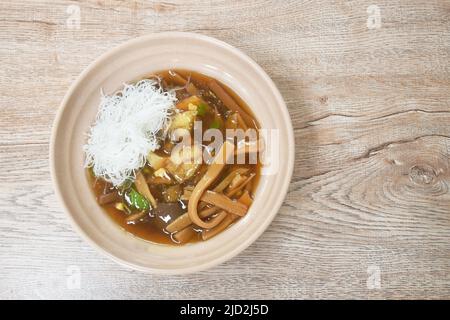 Geschmorte Fischpfote mit Bambusschiessen, die Hühnchen in Scheiben schneiden und gekochtes Ei in einer Suppe mit roter Soße, die Reis vermicelli auf der Schüssel gibt Stockfoto