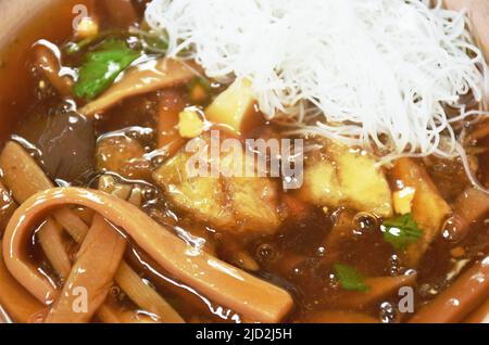 Geschmorte Fischpfote mit Bambusschiessen, die Hühnchen in Scheiben schneiden und gekochtes Ei in einer Suppe mit roter Soße, die Reis vermicelli auf der Schüssel gibt Stockfoto