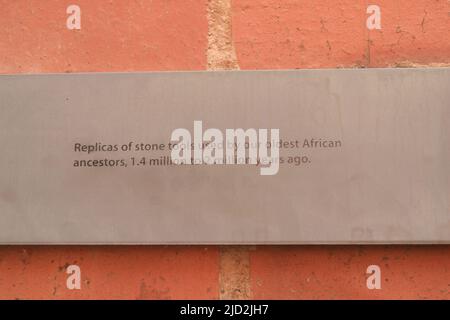 Schild an der Ziegelwand: Repliken von Steinwerkzeugen, die von unseren ältesten afrikanischen Vorfahren vor 1,4 Millionen bis 2 Millionen Jahren in der Ausstellung, Apartheid Museum, J, verwendet wurden Stockfoto