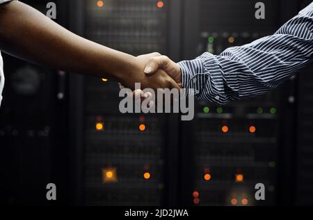 Gepaart für professionellen IT-Service. Eine kurze Aufnahme von zwei unkenntlichen Männern, die sich vor einem Server in einem Rechenzentrum die Hände schüttelten. Stockfoto