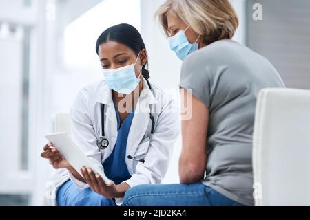 Diagnosetools erhalten ein digitales Upgrade. Aufnahme eines jungen Arztes mit einem digitalen Tablet während einer Konsultation mit einer älteren Frau. Stockfoto