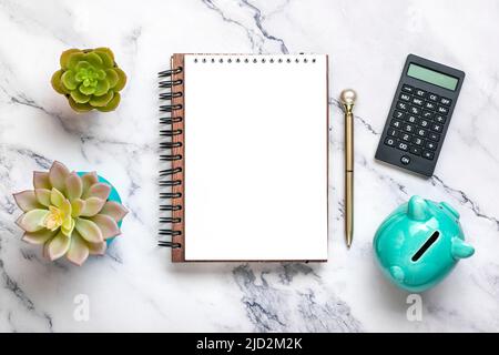 Notizblock, Sparschwein, Heimwerk, Rechner, Stift auf Marmorhintergrund Finanzplanung, Ziele, Projekt für Neujahrskonzept Draufsicht Flat Lay Financ Stockfoto