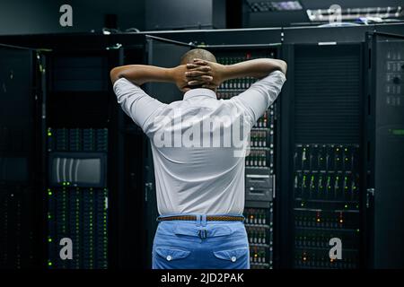 Wenn das Netzwerk unverbunden ist. Rückansicht eines IT-Technikers, der Schwierigkeiten hat, einen Computer in einem Rechenzentrum zu reparieren. Stockfoto