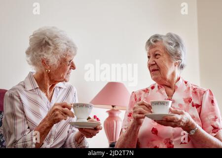 Der Nachmittagstee ist die perfekte Zeit für einen Nachholbedarf. Aufnahme von zwei glücklichen älteren Frauen, die zu Hause Tee trinken. Stockfoto