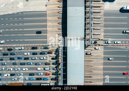 Ein Blick von oben auf eine stark befahrene Mautstraße mit vielen Autos, die Schlange stehen, um die Autobahngebühr zu bezahlen. Stockfoto