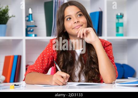 Denkende nachdenkliche Teenager Schulmädchen. Schüler schreiben im Übungsbuch, studieren im Klassenzimmer. Ernst Teenager Schülerin. Stockfoto