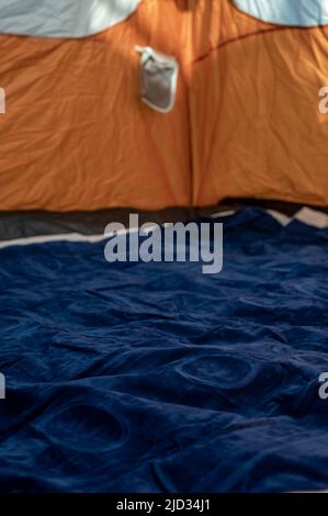 Selektiver Fokus einer aufblasbaren Luftmatratze auf dem Boden eines aufgefüllten Zeltes. Stockfoto