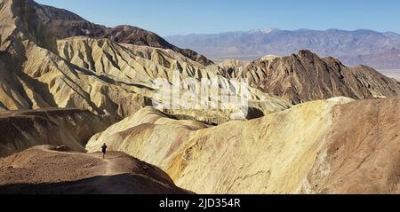 Ein Alleinwanderer erkundet einen Wanderweg an der Red Cathedral mit Blick auf den Golden Canyon im Death Valley National Park. Panamint Mountains in der Ferne. Stockfoto