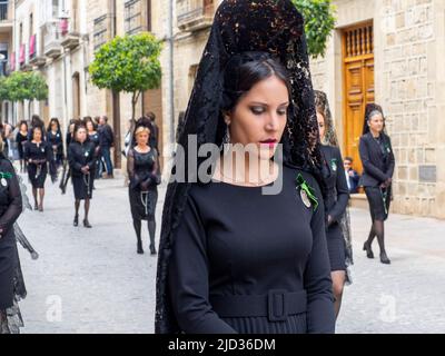 Frauen, die in der traditionellen Mantilla gekleidet sind, ziehen während der Karwoche durch die Straßen von Úbeda. Stockfoto