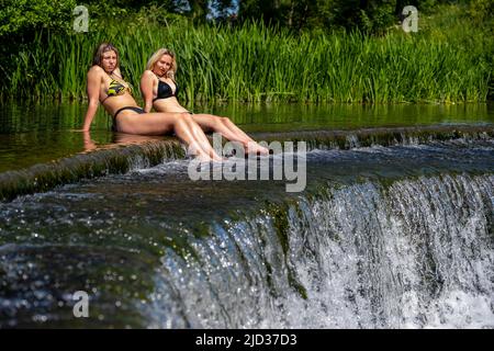 Die Menschen genießen das Wasser in Warleigh Weir am Fluss Avon in Somerset, während die Temperaturen über das Vereinigte Königreich steigen. Stockfoto