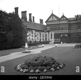 1940s, historisch, Rückseite der Bramall Hall, Stockport, England, Großbritannien. Das aus dem 14.. Jahrhundert stammende, mit Fachwerkrahmen umrahmte Tudor-Herrenhaus, das später erweitert wurde, wurde 1935 von der Stadtverwaltung erworben und zu einem Museum. Die Familie Davenport, von der angenommen wird, dass sie das Haus gebaut hat, hielt das Herrenhaus über 500 Jahre lang. Hier sehen wir einen Blick vom 1940s aus Richtung Westen, auf den Haupteingang, den Innenhof, den Südflügel und den Großen Saal in der Mitte. Stockfoto