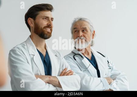 Zwei professionelle Ärzte in Uniform stehen im Krankenhaus mit Kreuzarmen Stockfoto