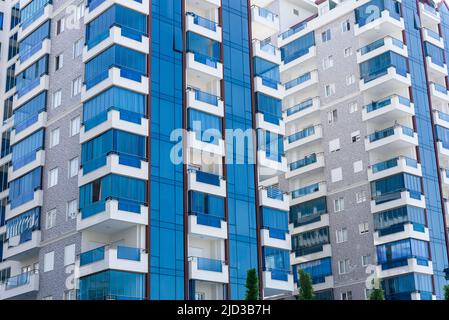 Abstrakte Ansicht eines Mehrfamilienwohnkomplexes von Eigentumswohnungen mit blau und weiß lackierten Fensterbalkonen. Hintergrundarchitektur. Stockfoto