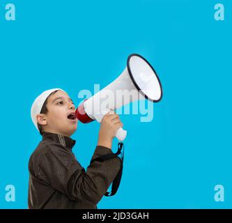 Kleiner Junge mit Megaphon, das auf blauem Hintergrund schreit. Hochwertige Fotos Stockfoto