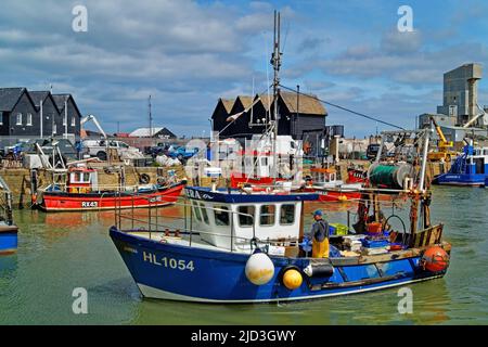 Großbritannien, Kent, Whitstable Harbour, Boats, Fishermans Huts und Brett Aggregates Ltd mit der Rückkehr des Fischerbootes in den Hafen. Stockfoto