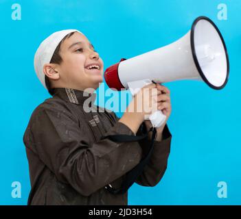 Kleiner Junge mit Megaphon, das auf blauem Hintergrund schreit. Hochwertige Fotos Stockfoto