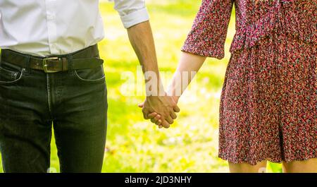 Halt durch, Hände, Paar. Paar hält die Hände am Sonnentag. Paar hält die Hand im Park. Paarhaltenden Hand. Junges Paar in der Liebe zu Fuß in Stockfoto