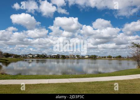 Orlando, FL USA-25. Februar 2022: Ein geschwungener Bürgersteig neben einem See, der ein Wanderweg hinter den Häusern im Laureate Park Lake Nona an Orlando, Flo ist Stockfoto