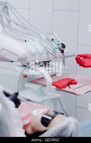 Die Hand des Zahnarztes legt einen Handschuh in der Nähe der zahnärztlichen Instrumente in der Zahnklinik an. Schließen. Hochwertige Fotos Stockfoto