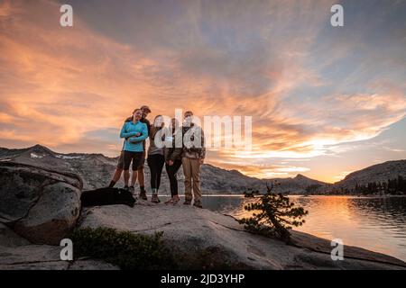 Eine Gruppe von Camper posiert vor einem angenehmen Sonnenuntergang am Lake Aloha Stockfoto