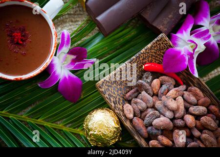 Eine Tasse Kakao und heiße Schokolade, Schokoriegel und Kakaobohnen auf grünen Palmblättern mit Platz für Ihre Kopie. Stockfoto