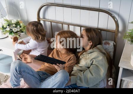 Drei Kinder schauen sich gemeinsam Videos an und haben Spaß im Kinderzimmer. Hochwertige Fotos Stockfoto