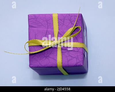 Dekorative lila Geschenkbox mit grüner Schleife auf blauem Hintergrund Stockfoto