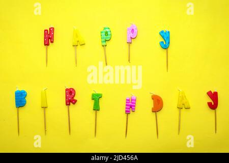 Happy Birthday Text dekorative bunte Wachskerzen Zeichen auf gelbem Hintergrund Stockfoto