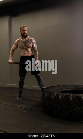 Vorschlaghammer Trucker Rad Straße Reifen Frau ersetzen junge Hammer Turnhalle, für Geräte Konzentration von Mann aus Muskeltraining, Mann Erwachsene Stockfoto