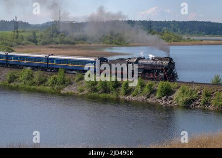 HELULYA, RUSSLAND - 11. JUNI 2022: Dampflokomotive L-0522 mit touristischem Retrozug 'Ruskeala Express' auf dem Damm des Karmalanyarvi Sees Stockfoto