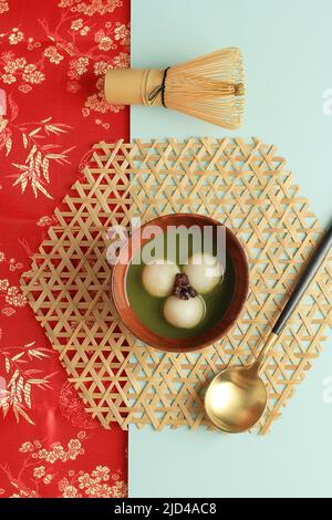 Matcha Tangyuan oder Tang Yuan mit süßer Matcha-Suppe in Holzschale, rotes chinesisches Konzept für Festessen zur Wintersonnenwende. Draufsicht Stockfoto