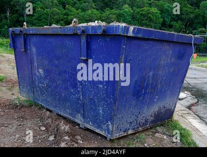 blue Metal Waste skip, gefüllt mit Hausmüll auf der Baustelle Stockfoto